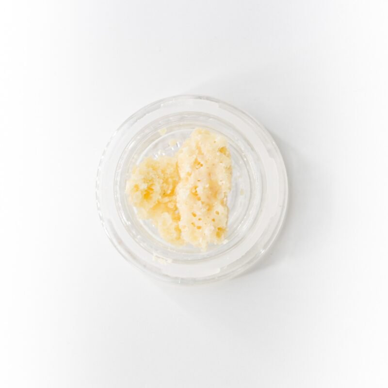 Close-up of White Fire OG Crumble Concentrate Wax from Monster of Terps in a clear container, showcasing its golden, crumbly texture.